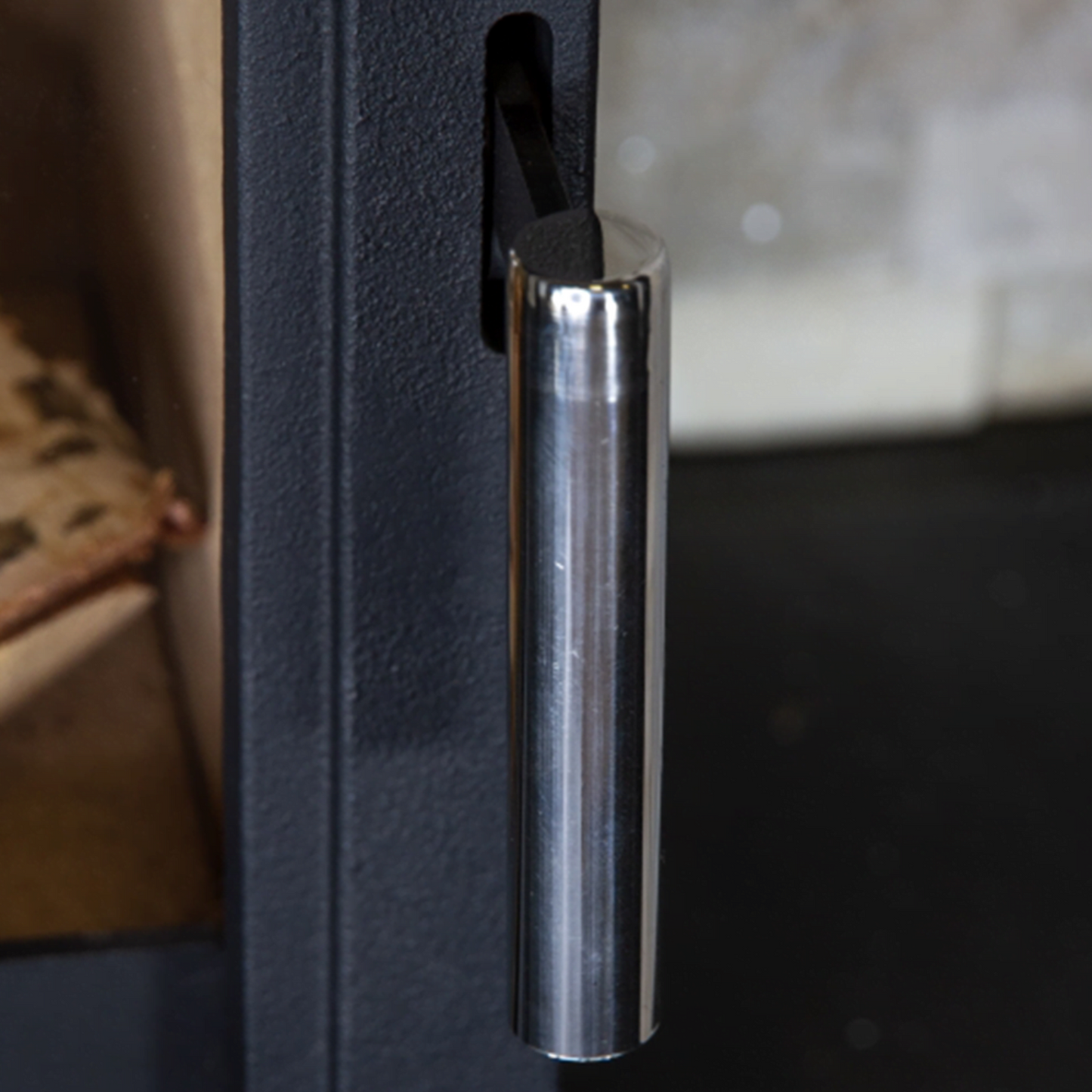 Close-up of a metallic handle on a black stove