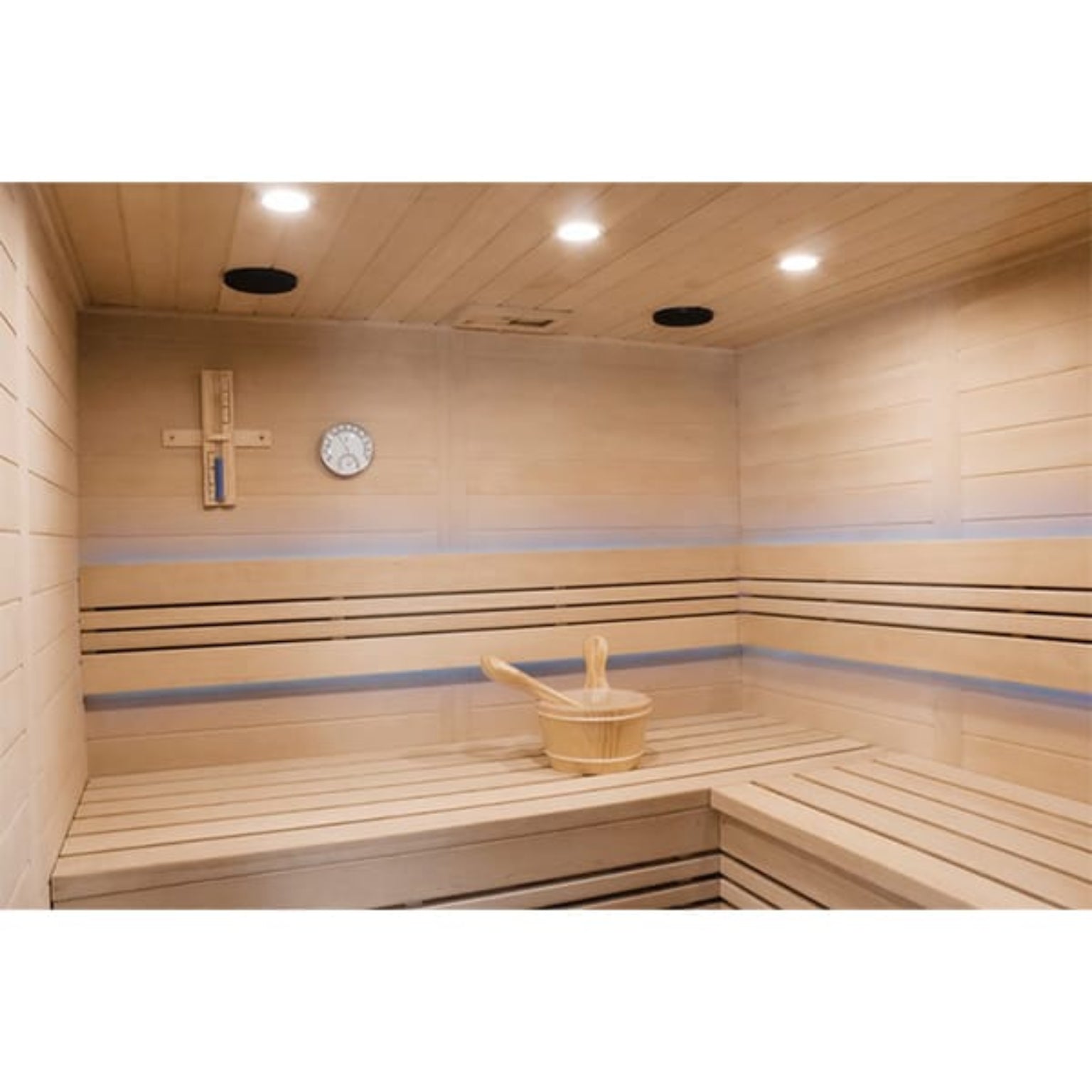 Wooden sauna interior with a thermometer and wooden bucket.